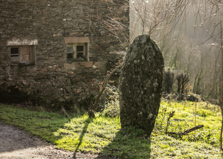 Statue-menhir près d'un bâtiment en pierre, l'hiver