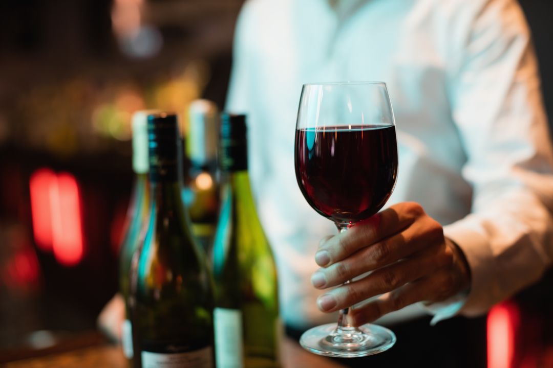 Bartender holding glass of red wine
