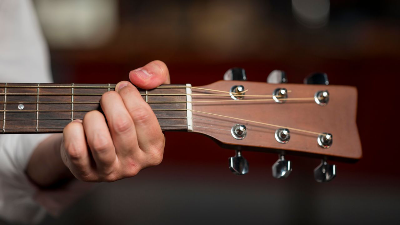 close-up-man-holding-chord-guitar