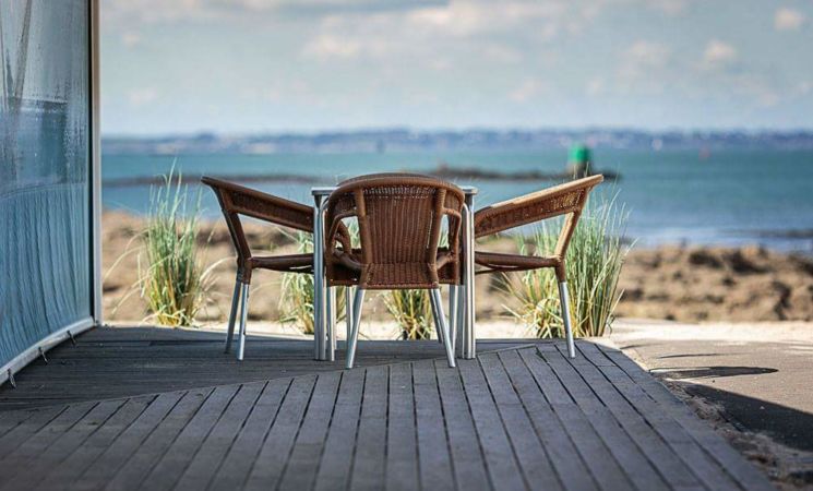 Table en terrasse au restaurant La Grande Plage, avec vue sur mer et sur l'île de Groix, sur la grande plage de Port-Louis, près de la Citadelle (Morbihan, Bretagne Sud).